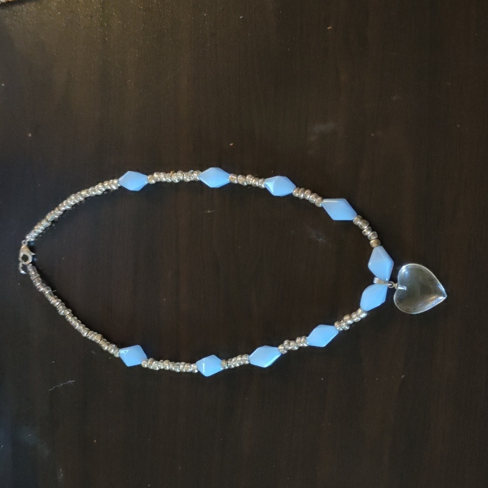 Glass heart necklace with blue and silver beads.